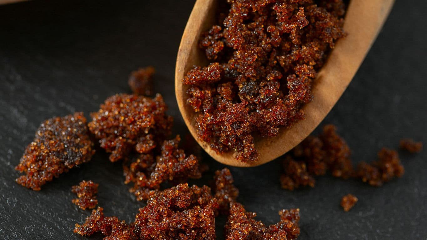 Close-up of brown sugar crystals on wooden spoon