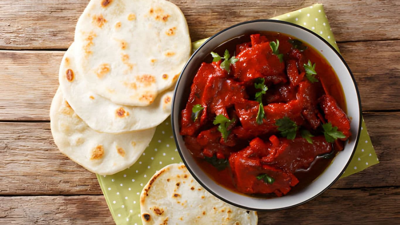 Indian curry with naan bread on wooden table