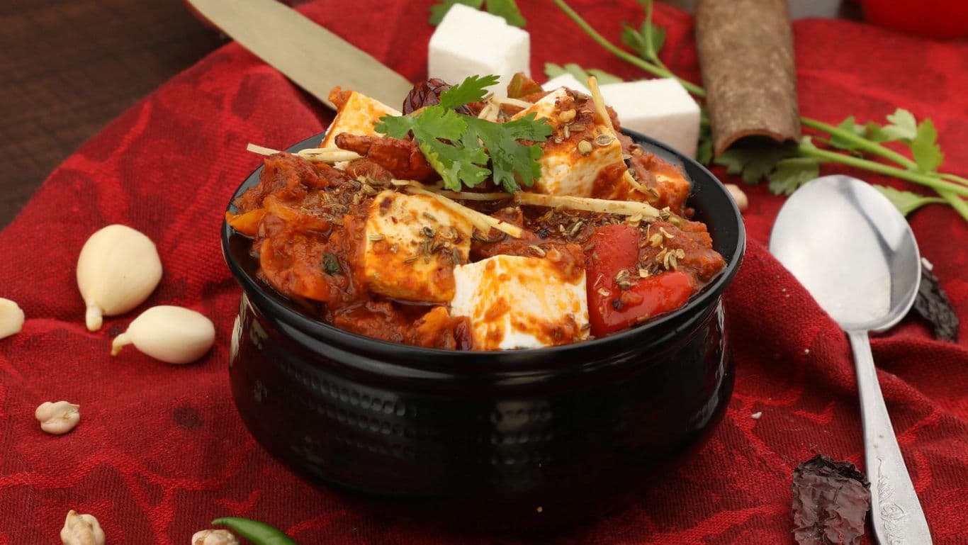 Spicy paneer curry in black bowl