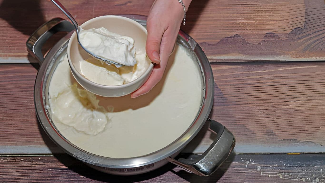 Scooping Fresh Yogurt from Metal Pot into Bowl