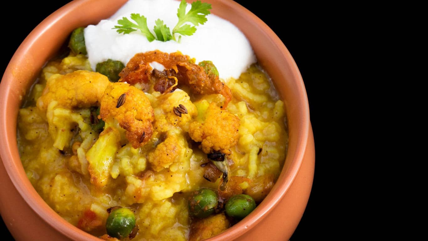 Vegetable khichdi with yogurt in clay bowl