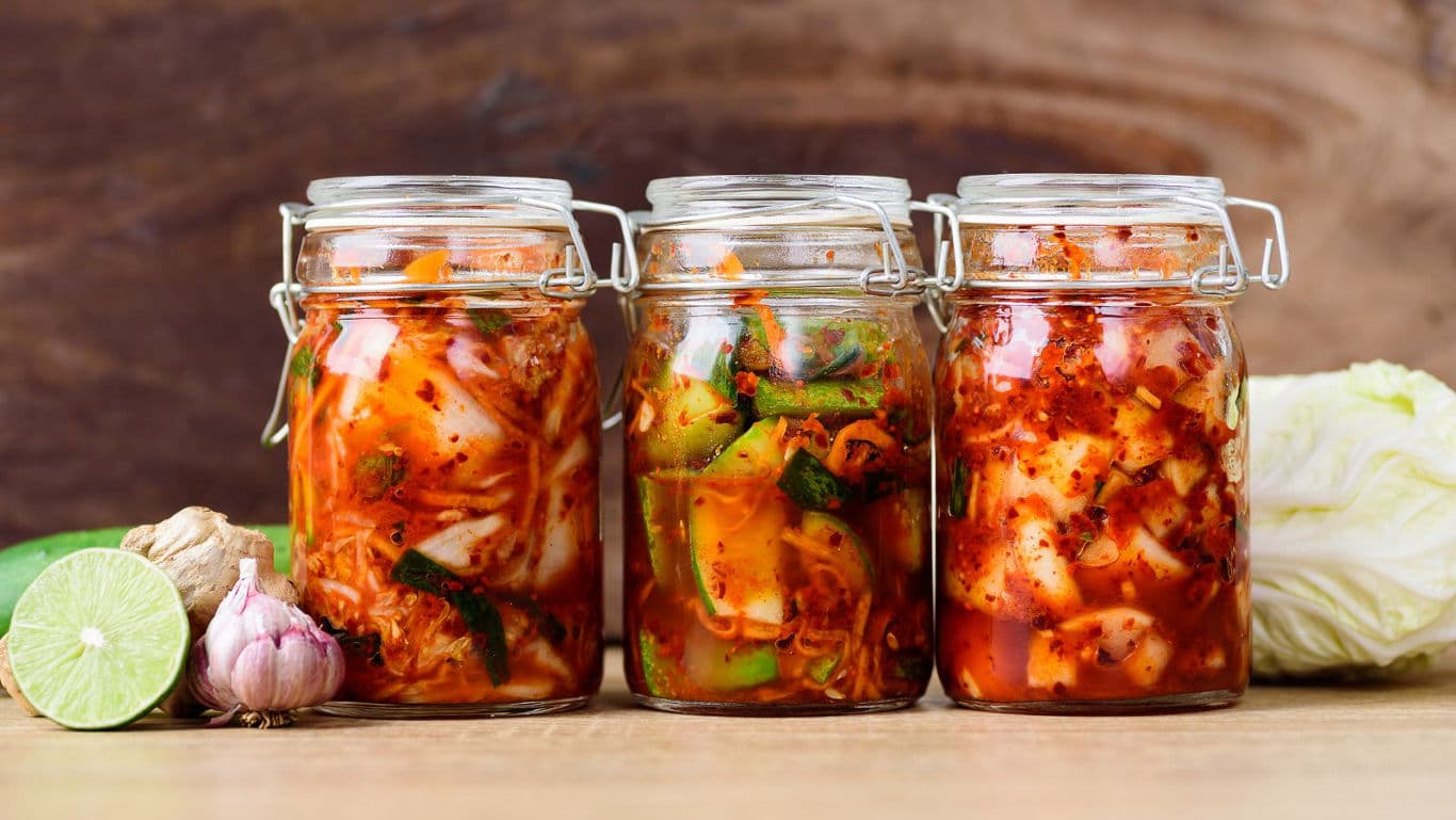 Three jars of homemade kimchi on table