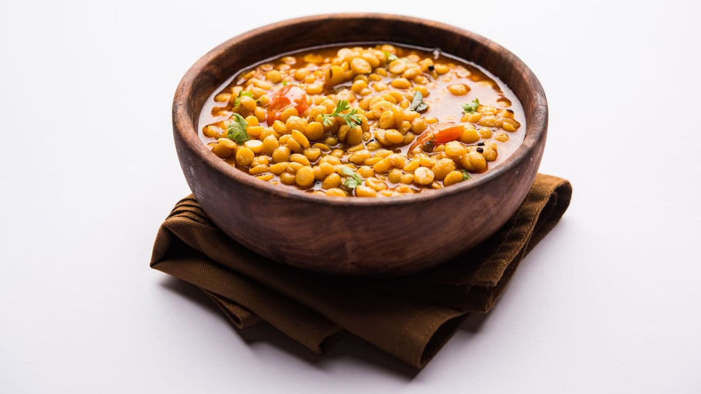 Wooden bowl of lentil curry on cloth
