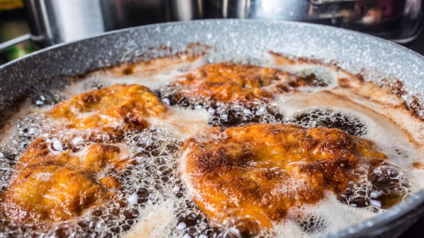 Golden fried food sizzling in pan