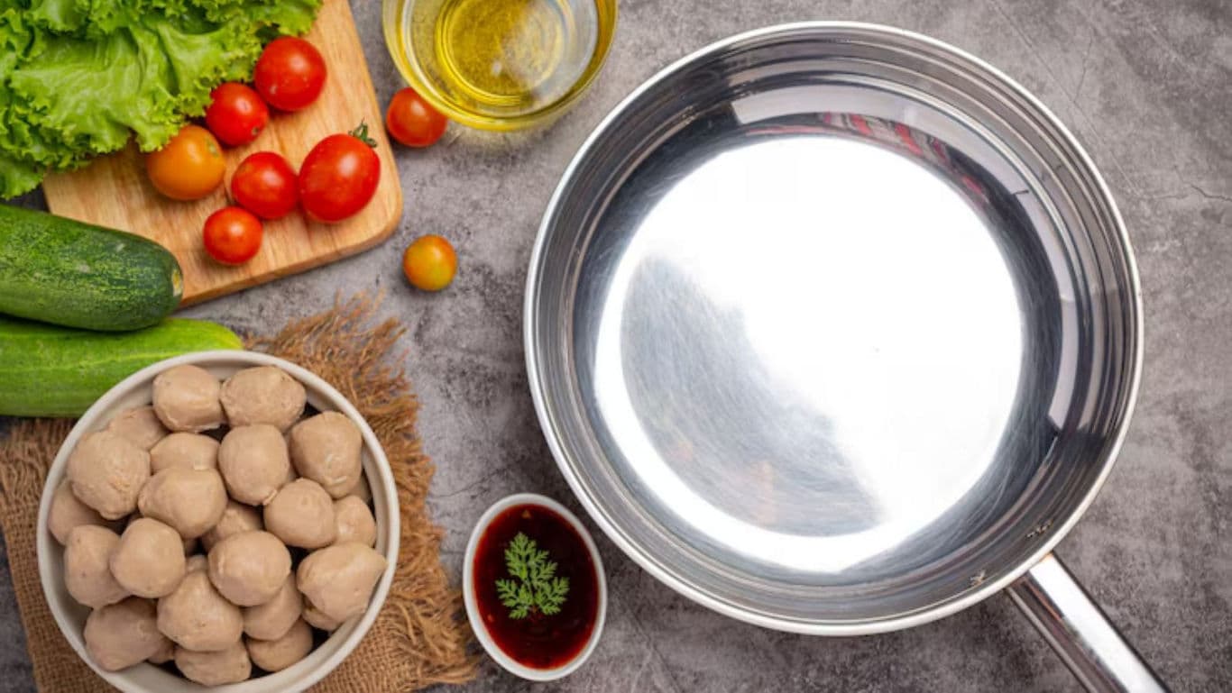 Fresh vegetables and meatballs beside empty metal pot