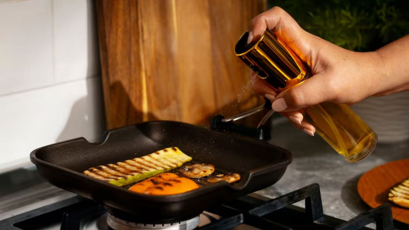 Hand Sprays Oil on Grilled Vegetables in Pan