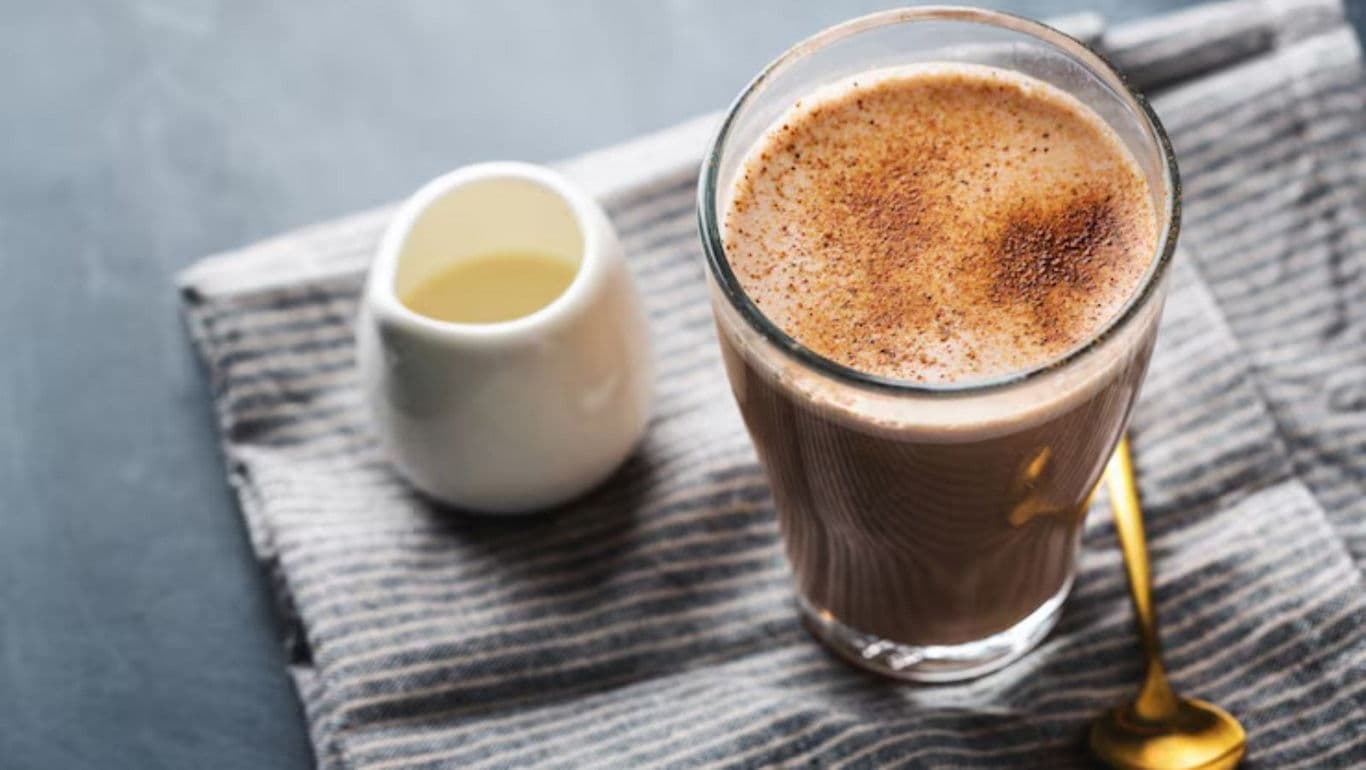 Glass of Hot Chocolate with Creamer on Table