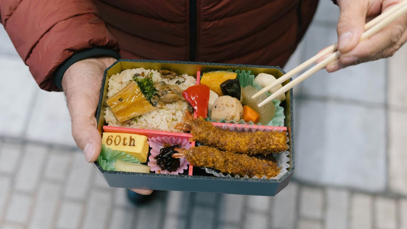 Hand holding bento box with chopsticks