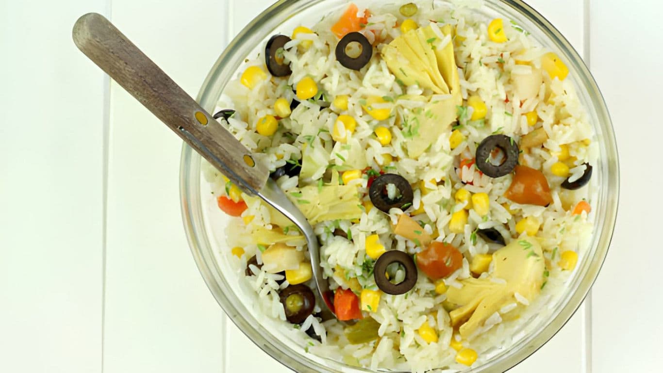 Colorful rice salad with vegetables and olives in bowl
