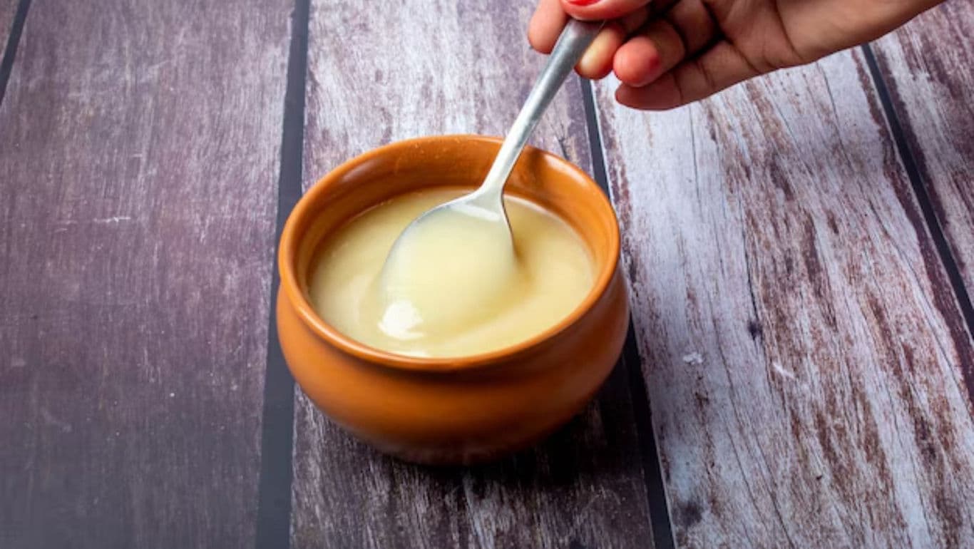 Hand holding spoon with creamy dessert in bowl