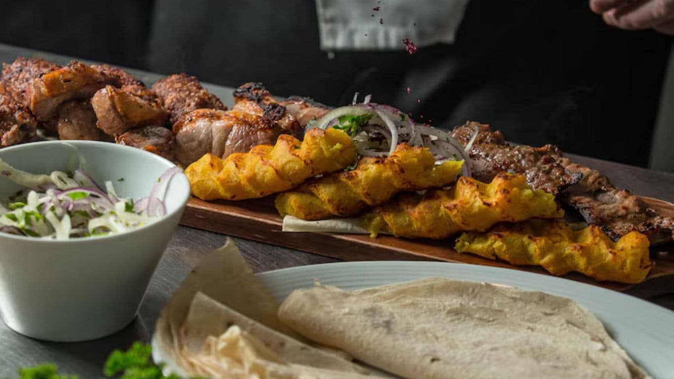 Grilled meat skewers with sides on table