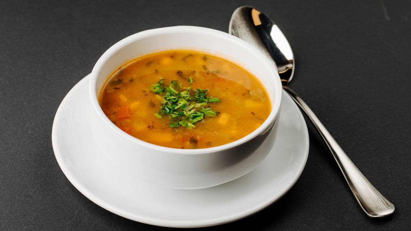 Bowl of hearty vegetable soup on table