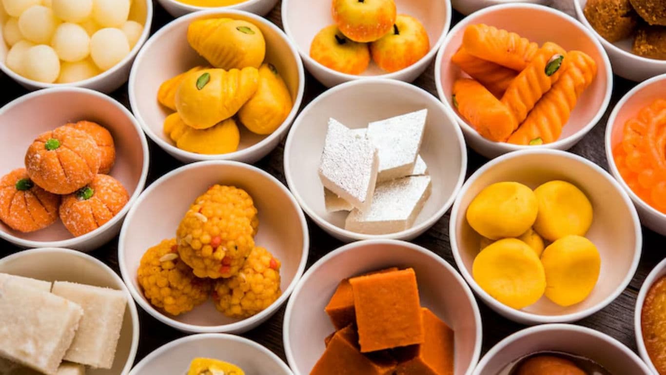 Assorted Indian sweets in white bowls