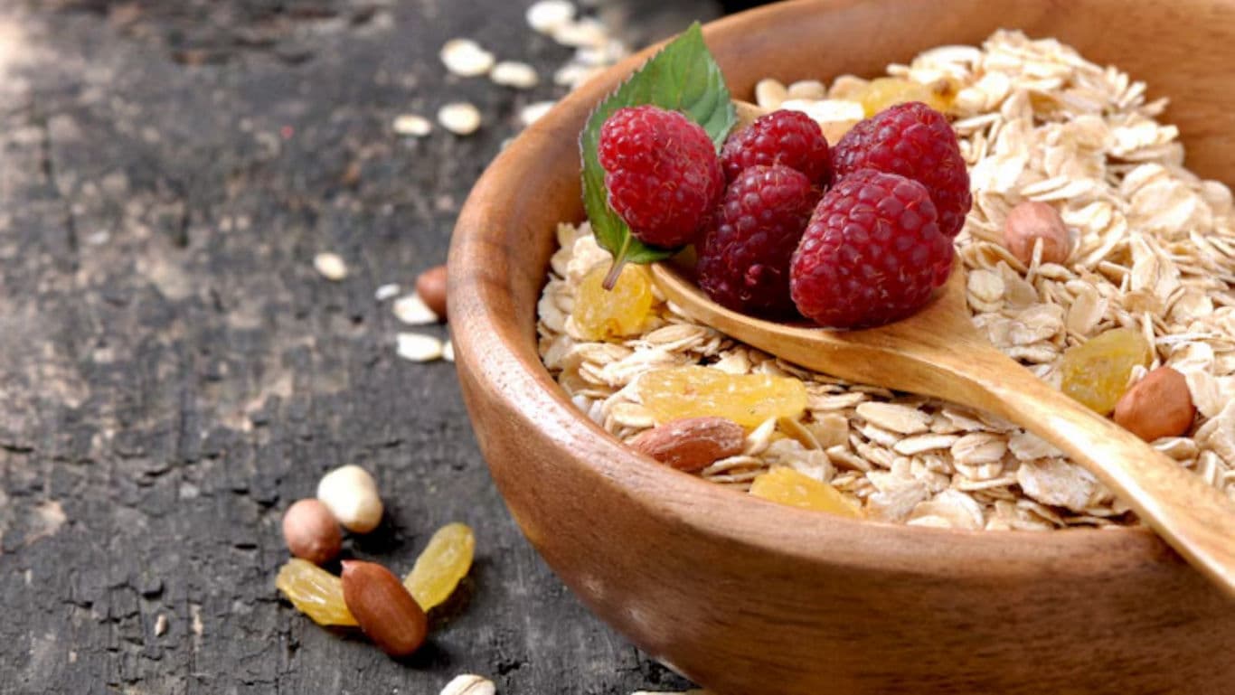 Wooden bowl of oats with raspberries