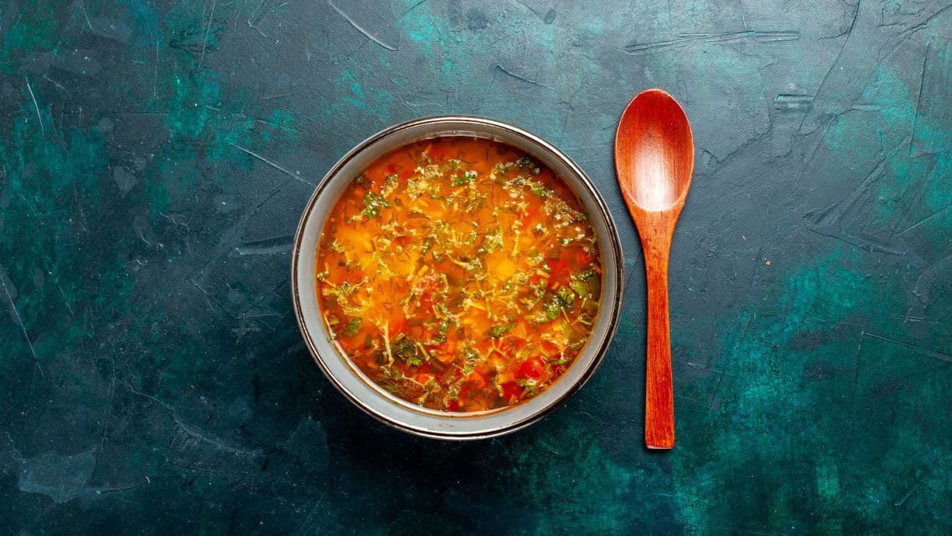 Bowl of vibrant vegetable soup with spoon