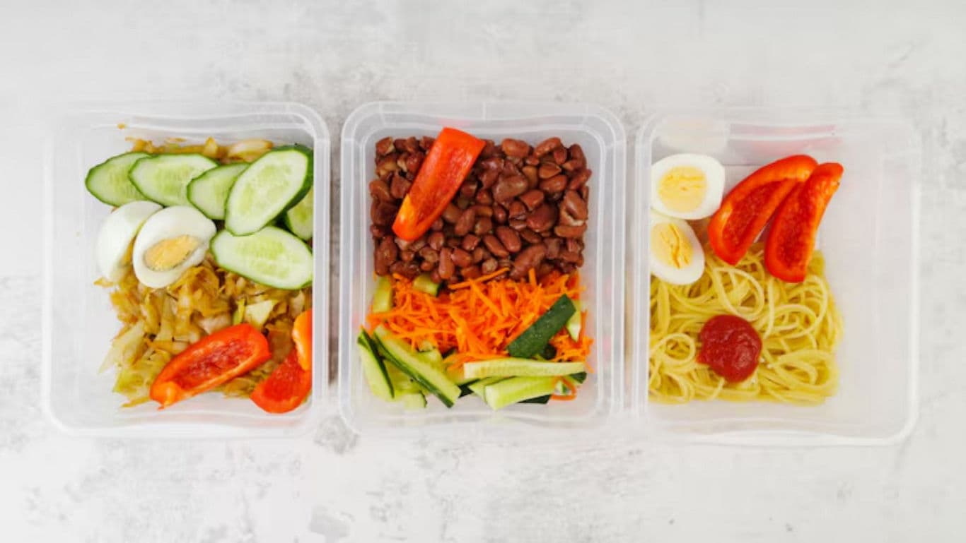 Three healthy meal prep containers with vegetables and eggs