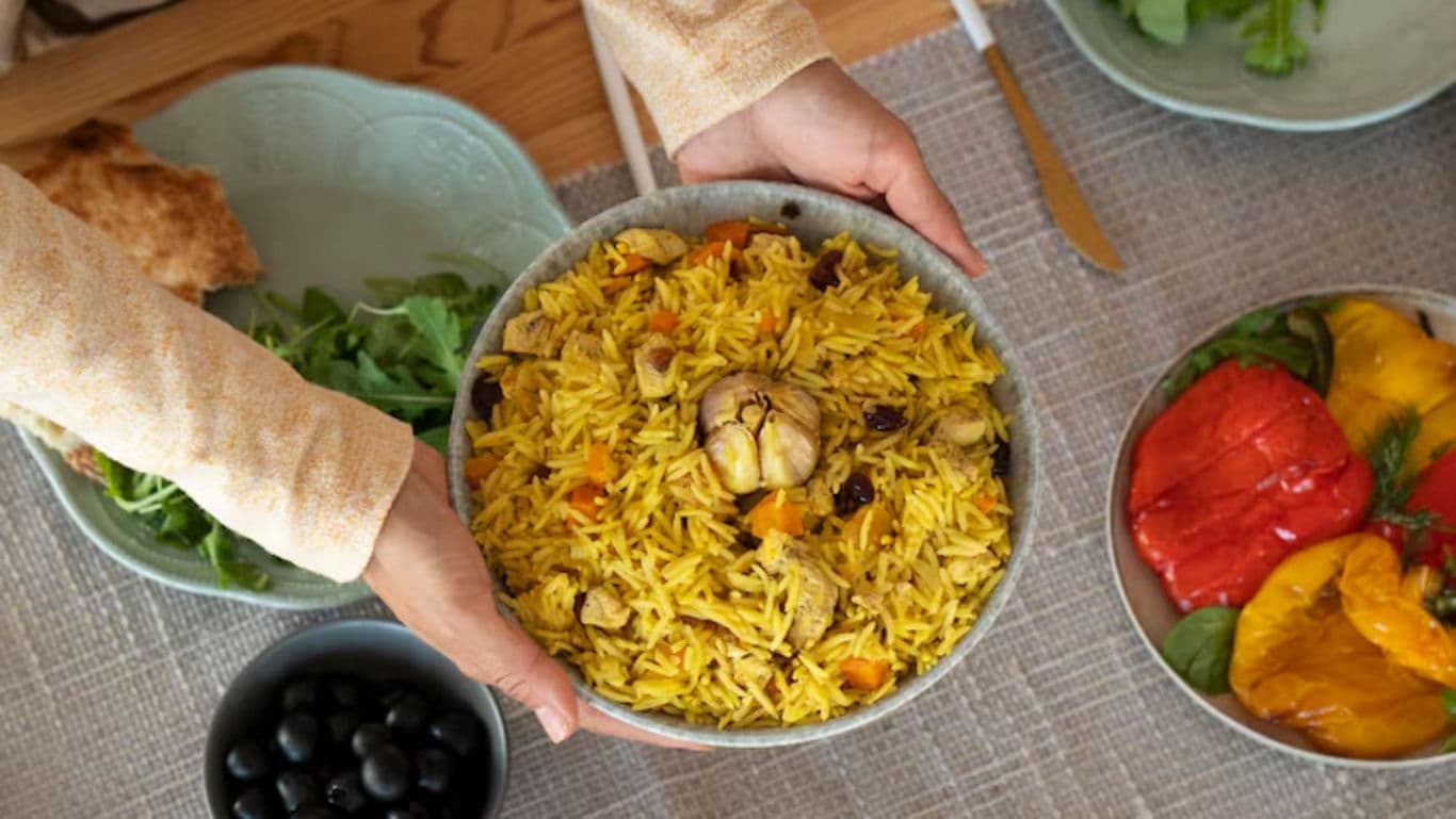 Hands serving saffron rice with vegetables