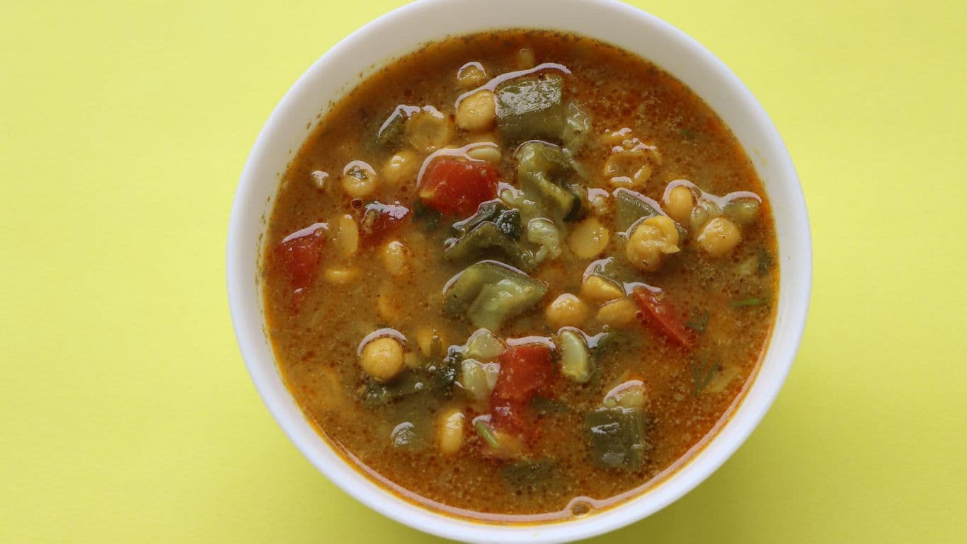 Bowl of vegetable chickpea soup on yellow