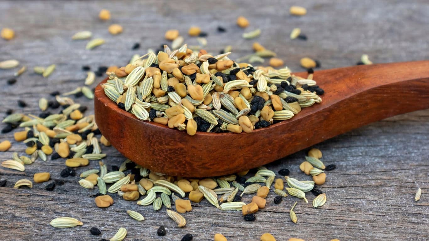 Wooden spoon with mixed seeds on table