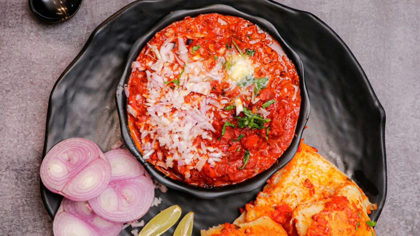 Indian pav bhaji served with onions and lemon wedges