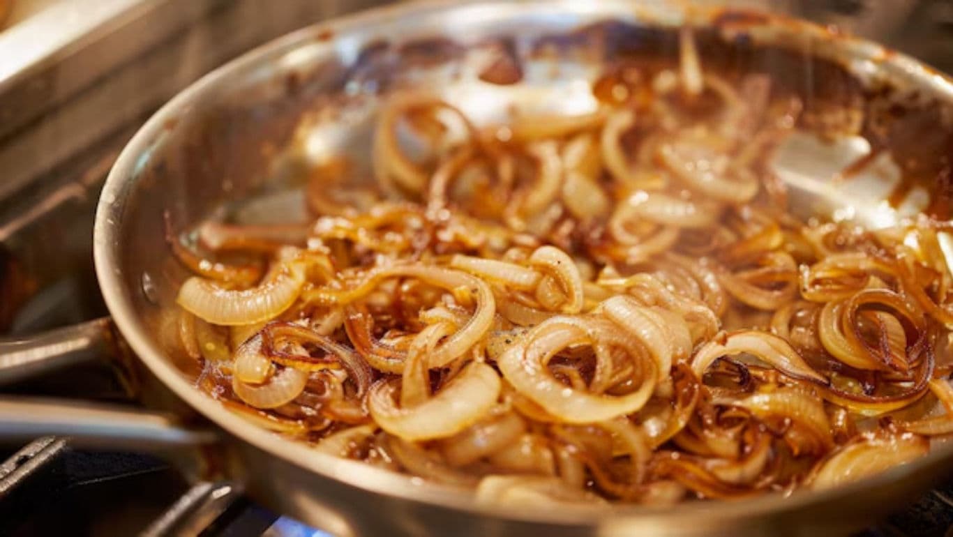 Caramelized onions cooking in stainless steel pan