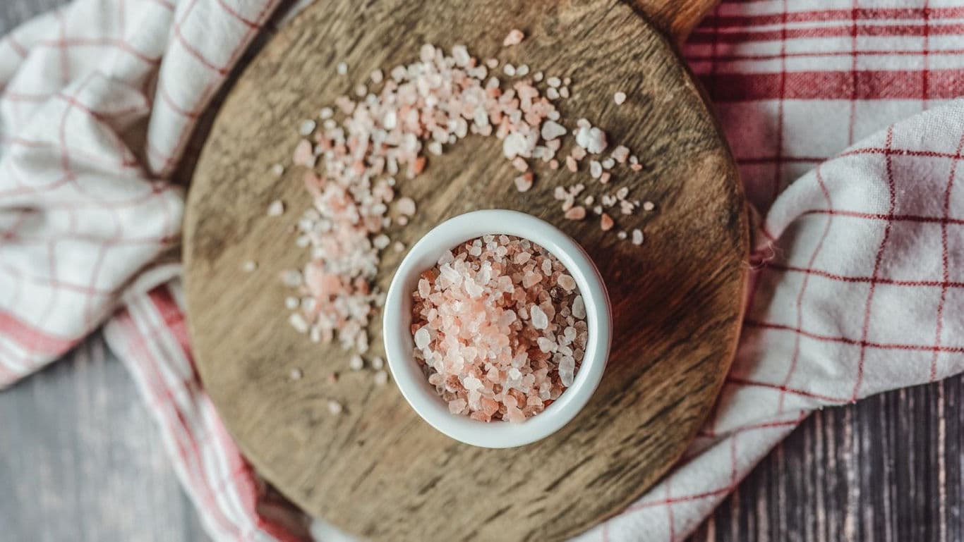 Pink Himalayan salt in white bowl on wood