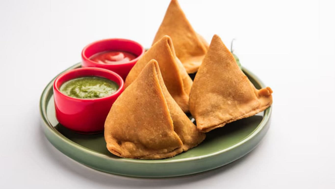Plate of crispy samosas with chutneys