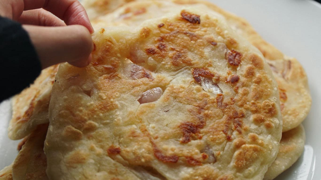 Hand picking freshly cooked flatbread from plate