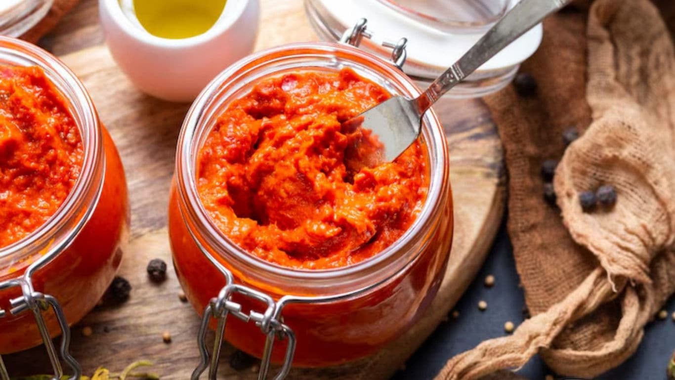 Jars of red pepper spread on rustic wooden board