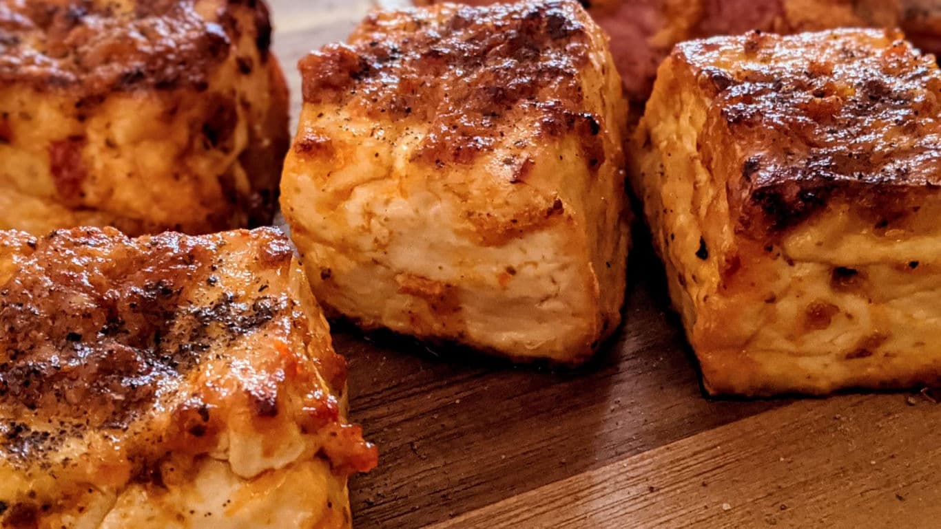 Golden baked cheese cubes on wooden surface