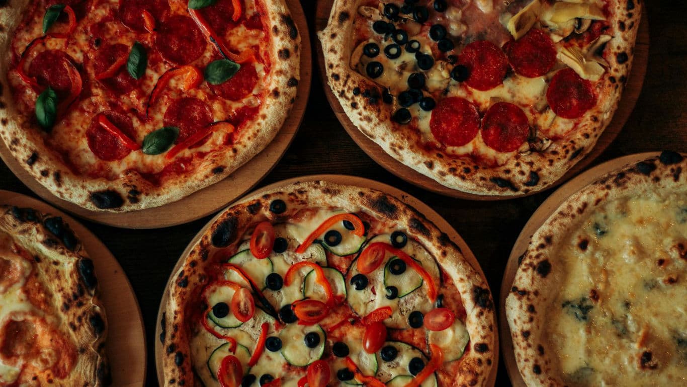 Assorted gourmet pizzas on wooden plates