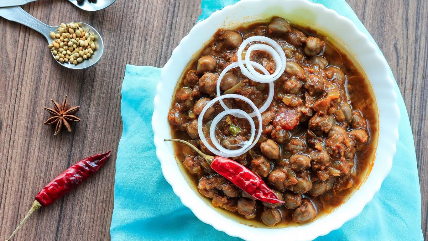 Spicy chickpea curry with onions and chili garnish