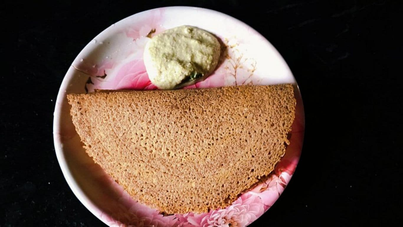 Brown dosa with chutney on floral plate