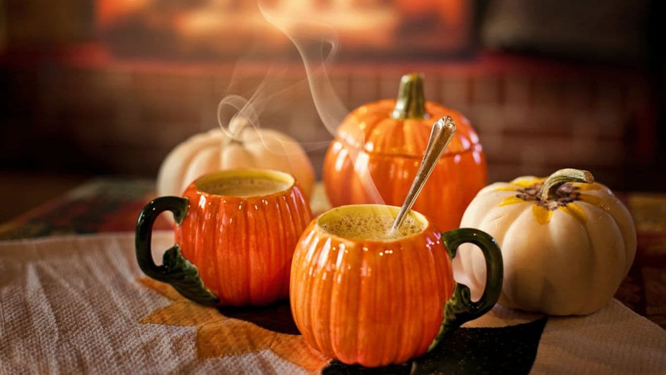 Pumpkin-themed mugs with steaming drinks