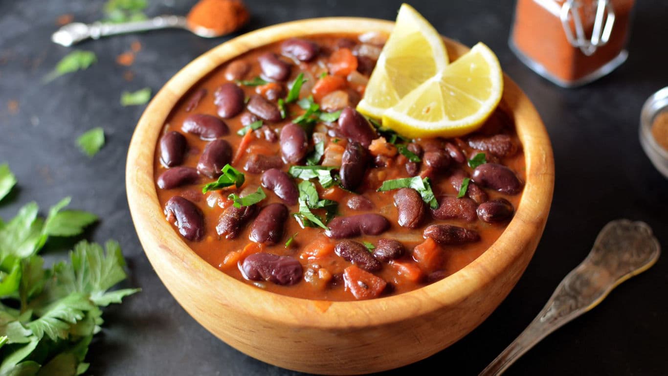 Wooden bowl of kidney bean stew with lemon