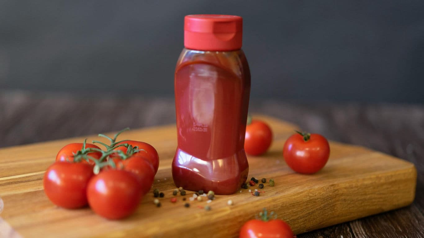 Tomato ketchup bottle with fresh tomatoes
