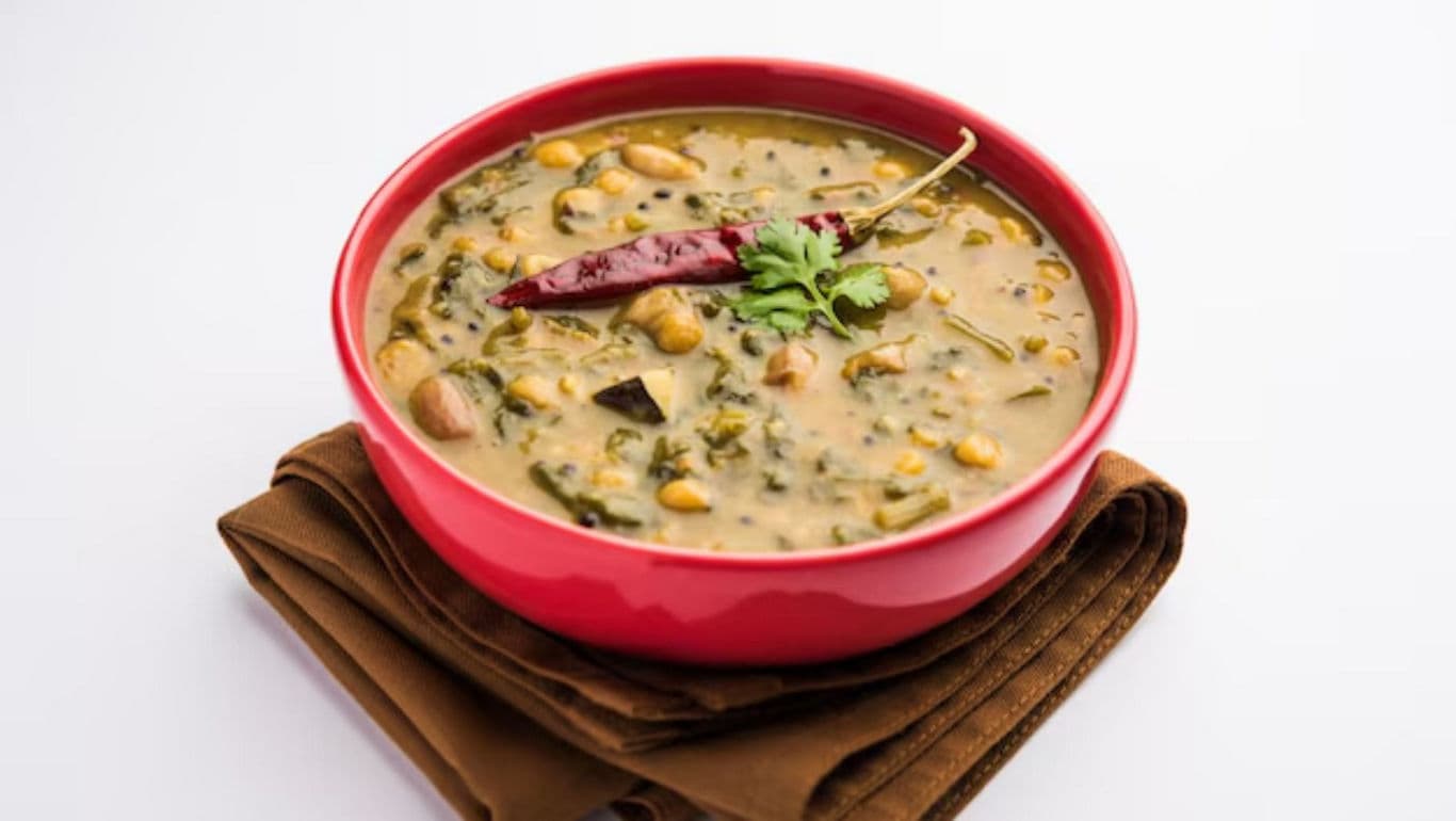 Red bowl of lentil curry with chili garnish
