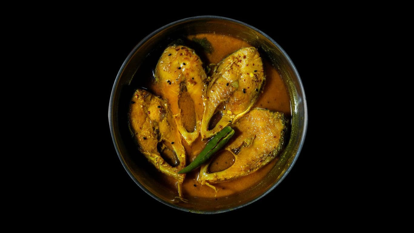 Fish curry in a bowl on black background