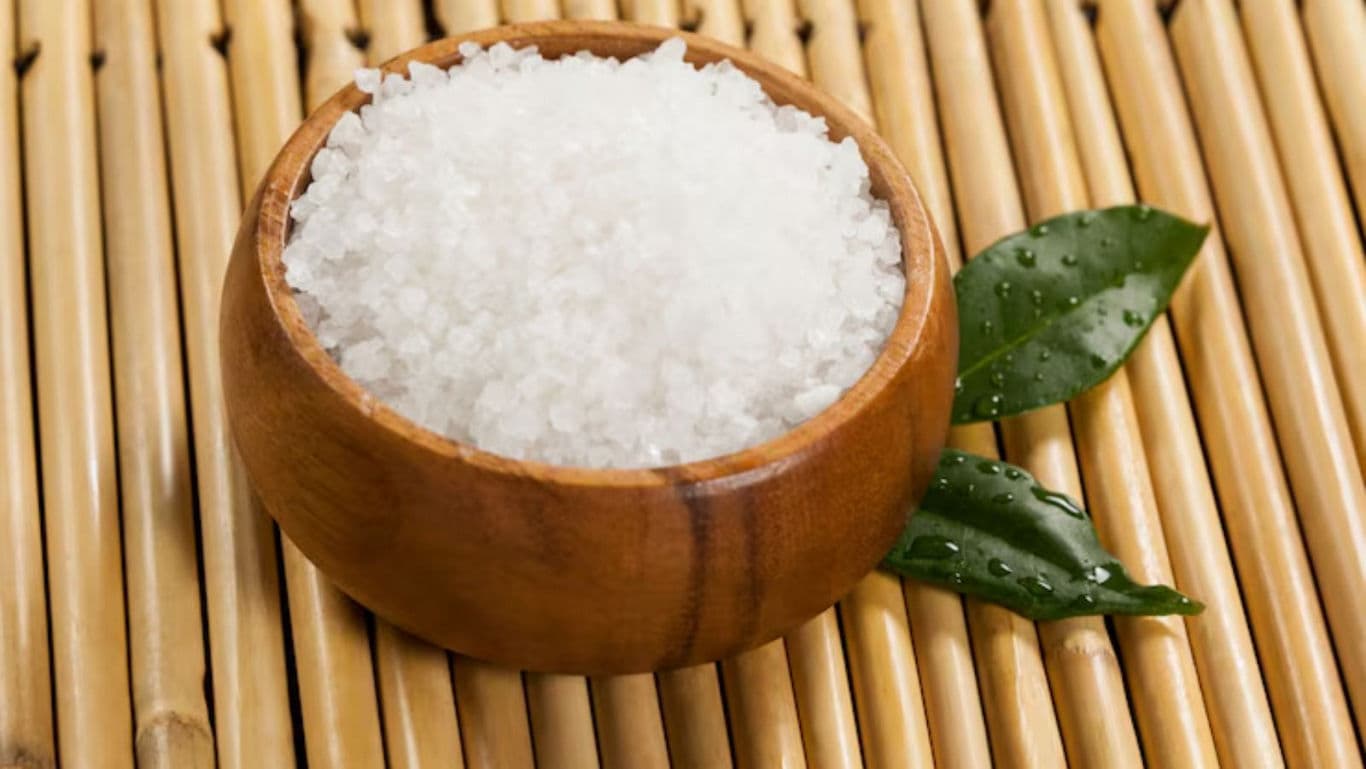 Wooden bowl of coarse salt on bamboo mat