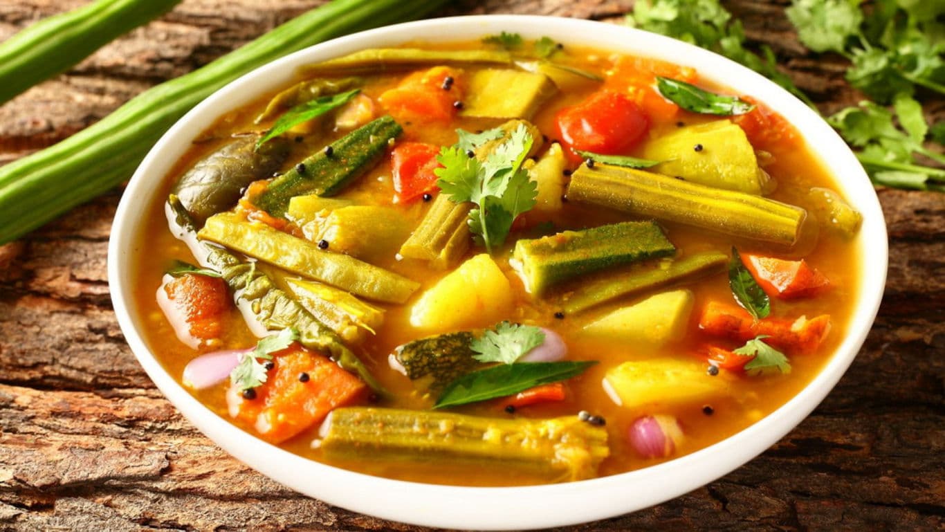 Bowl of South Indian vegetable sambar on rustic wood