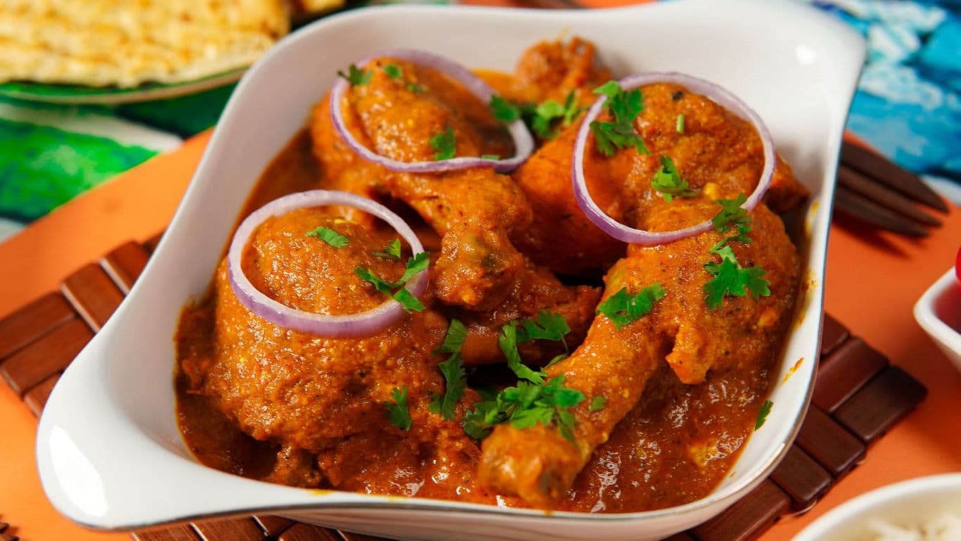 Spicy chicken curry garnished with onions and cilantro