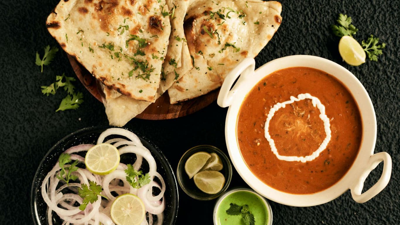 Indian curry with naan bread and fresh garnishes