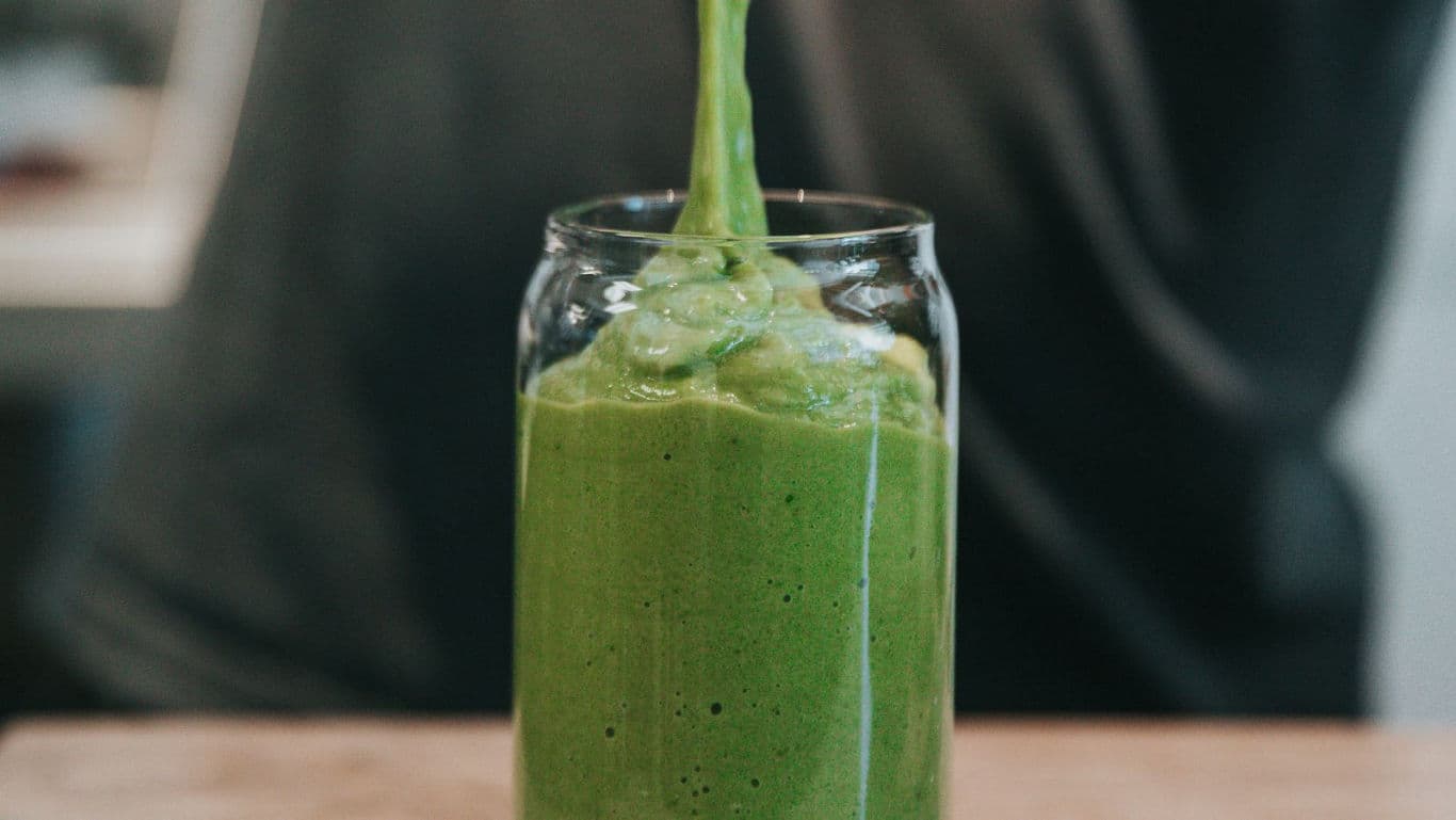 Green smoothie poured into clear glass jar