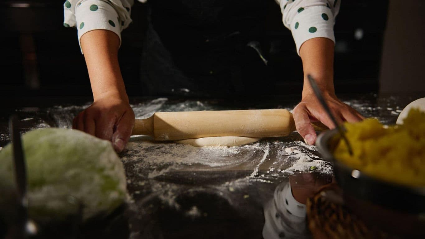 Person rolling dough in kitchen setting