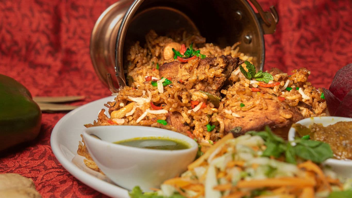 Aromatic Eid biryani served in a clay pot bowl with mint and fried onions on top.