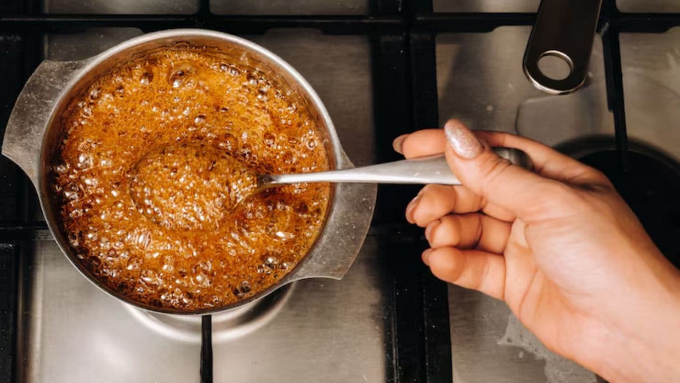 Hand Stirring Caramel Sauce in Saucepan on Stove