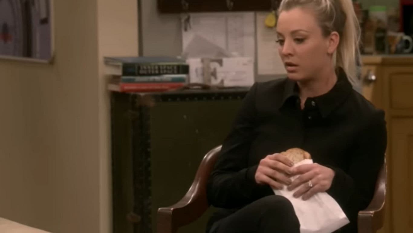 Woman seated holding wrapped sandwich indoors