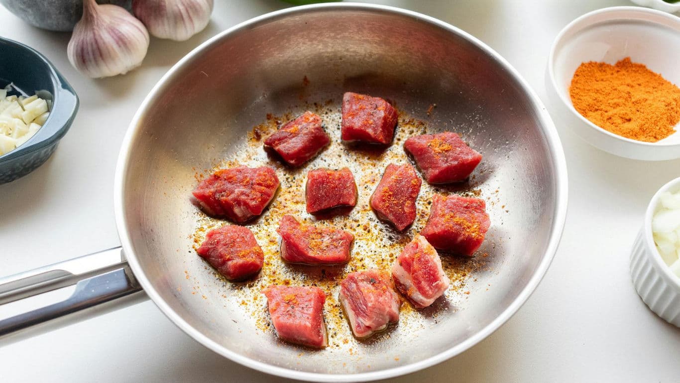 Seasoned meat cubes frying in pan