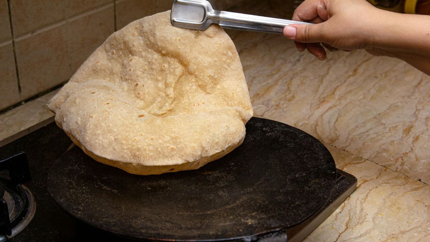 Homemade roti puffing on hot iron griddle