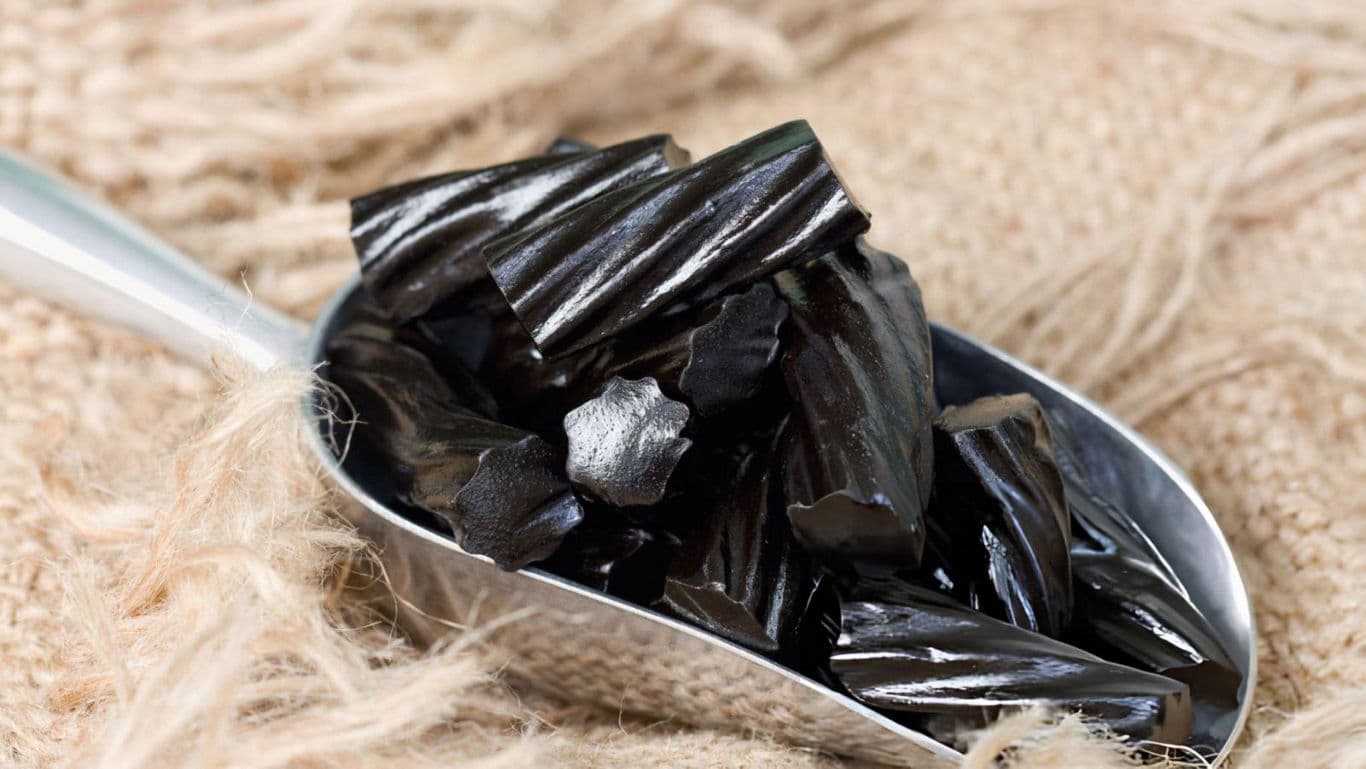 Black licorice pieces in metal scoop